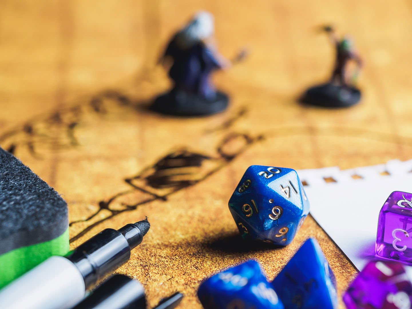 Markers, multi-sided dice, game pieces, and writing on a tap signifying a Dungeons and Dragons game being played