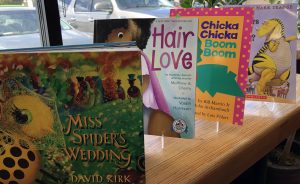 dr. seuss alternative books like Hair Love and Miss Spider's Wedding on a shelf in front of a window
