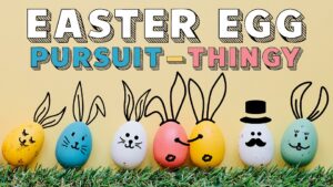 Beige background. Yellow, teal, green, pink, and white dyed easter eggs with drawn on faces and ears sitting on green grass. Wording on top in foreground "Easter Egg" in white, "pursuit" in teal, hyphen in yellow, "thingy" in pink