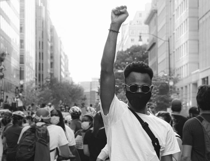 young black man with his arm up at a protest