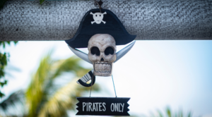 Banner image with a pirate skull hanging on a window holding a sign that says "Pirates Only"