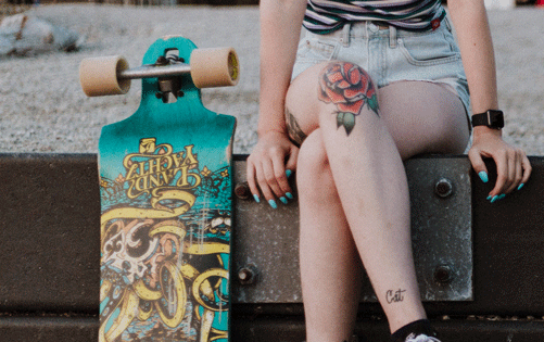 woman crossed legs rose tattoo on knee with skakeboard