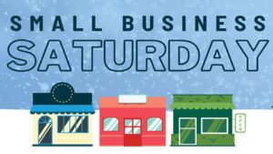 Blue flurry background on top 2/3. White snow bottom third background. 3 small buildings in bottom foreground. Blue "Small business Saturday" in top foreground