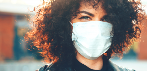 curly haired woman wearing a face mask in pubic